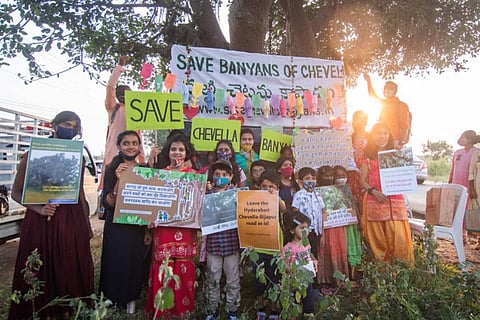 Children under a Banyan holding 'Save Banyans of Chevalla' posters