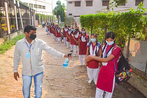 A line of students using sanitizer before entering school 