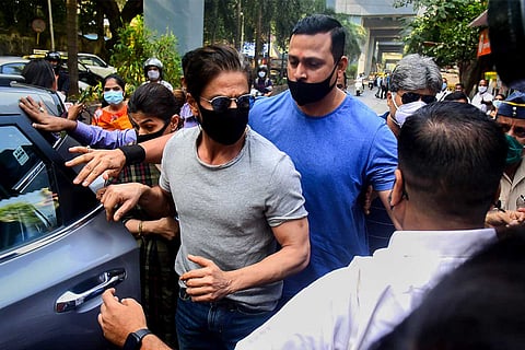 Shah Rukh Khan in a grey T shirt and black mask coming out of jail after visiting Aryan Khan