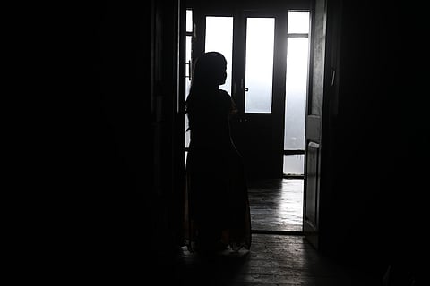 Silhouette of a girl standing against a door