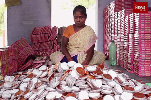 A woman fireworks worker sits before a pile of crackers at a factory in Sivakasi 