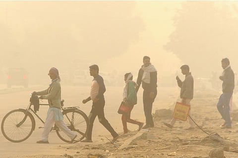 A group of people crossing the road in smog-filled Gurugram