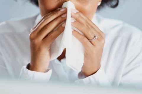 A woman sneezing with tissue