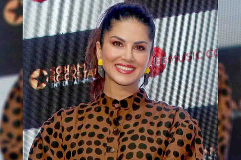 Sunny Leone wearing a brown and black top looking ahead and smiling