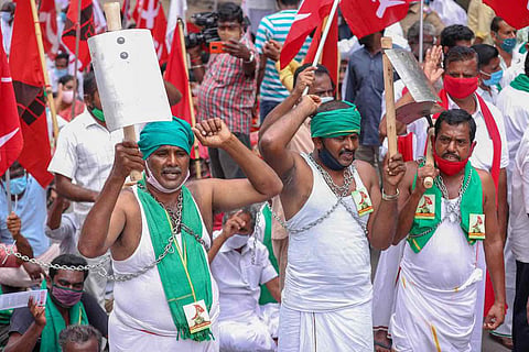 A group of farmers protesting with a green towel tied to their head and raising flag and slogans 
