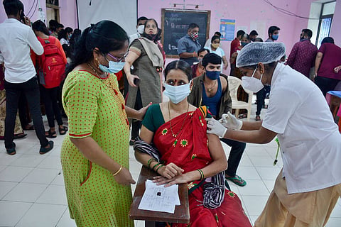 A health worker administering COVID vaccine to a teacher 
