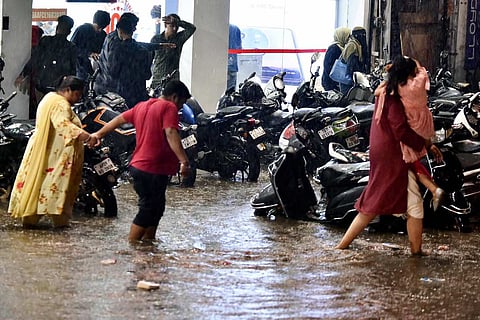 Commuters wade through a waterlogged street following rain in Hyderabad,