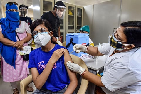 A woman in blue T-shirt getting vaccinated by a nurse