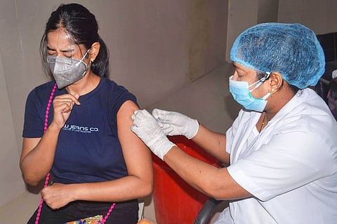 A woman receiving COVID-19 vaccine from a health worker