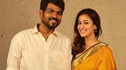 Vignesh Shivan and Nayanthara clad in shirt and saree respectively, facing the camera and smiling.