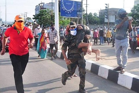 A police personnel carrying an unconscious man and running to save him 