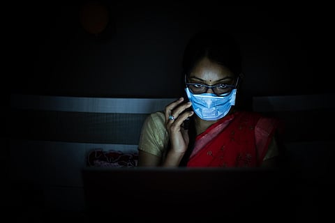 Woman wearing a red saree and mask working on laptop