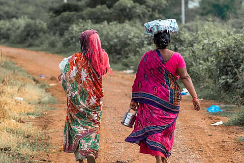 Two women walking on a mud road