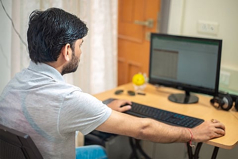A man wearing a white shirt working on a computer 