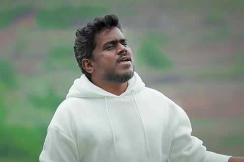 Yuvan Shankar Raja is seen singing in the backdrop of trees in the image.