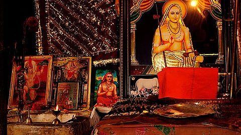 A prayer room with framed pictures of various Hindu gods and saints. The largest of them is a picture of Adi Shankaracharya placed on the right side.