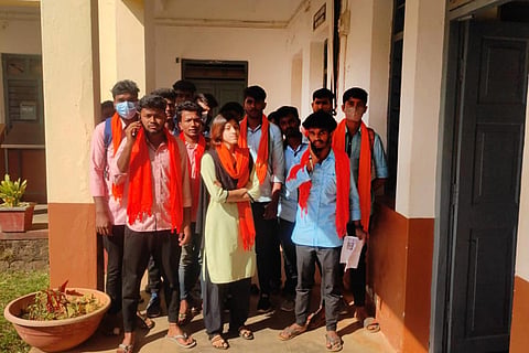 Students in Chikkamagaluru college standing outside a classroom wearing saffron scarves