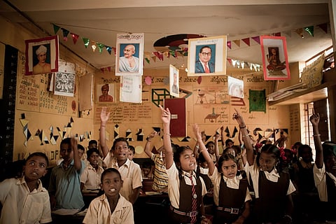 Children raising their hands in school