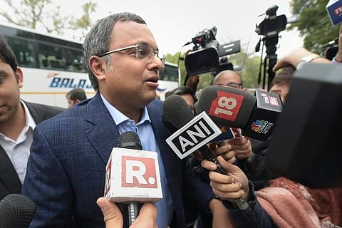 Karti Chidambaram wearing a coat speaking to media , in front of him are seen television mikes 