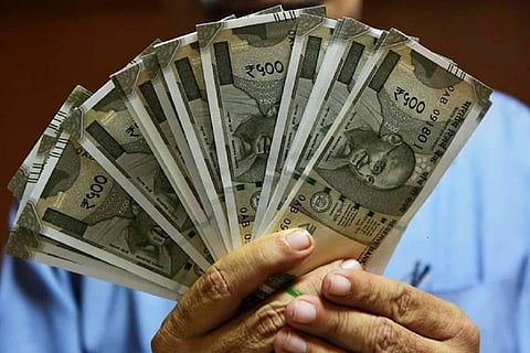A man holding up Rs 500 notes fanned out in front of his face