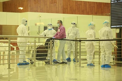 Passengers arriving at Cochin airport in Kerala wearing mask and staff in PPE kit waiting to screen them 