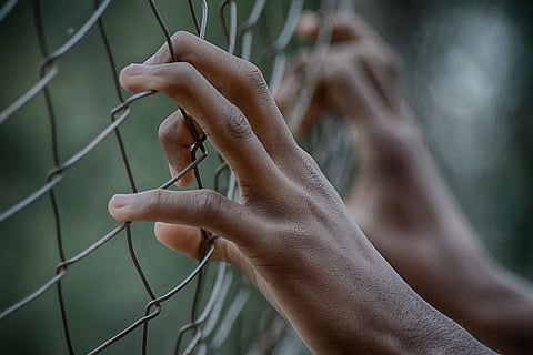 A person holding onto a fence 