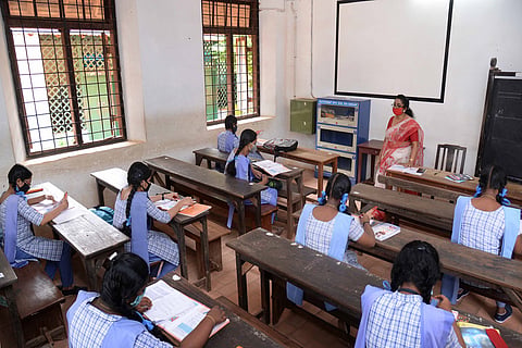 Girl students in uniform in a classroom in Kerala while a teacher taking the class 