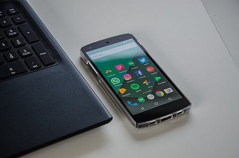 A smartphone with apps like Facebook, instagram, whatsapp next to a laptop