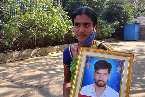 Manjula, wife of Raveender, holding a photo of her dead husband