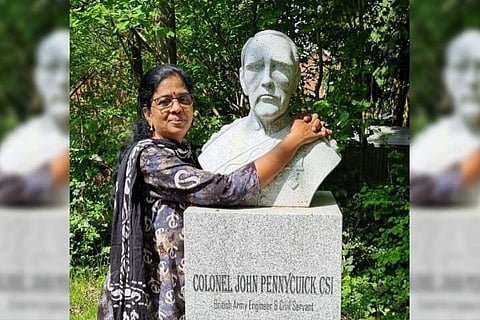 Tamil writer A Vennila standing next to a bust of British engineer John Pennycuick 