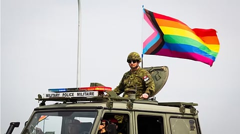A member of the military police stands with a rainbow Pride flag during 3rd Canadian Division Support Base Edmonton's second annual Pride parade