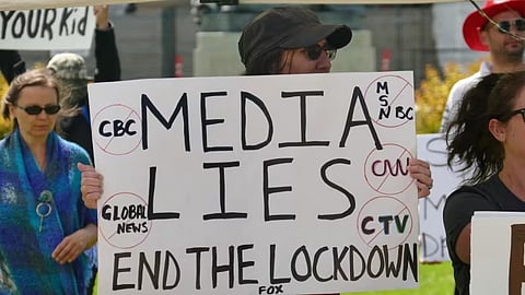 A protester holds a sign accusing the media of lying during an anti-lockdown protest in Winnipeg in July 2020.