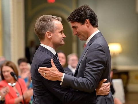 Prime Minister Justin Trudeau embraces Seamus O'Regan, minister responsible for Labour and Seniors, at his swearing in to Cabinet. O'Regan is now trying to persuade Canadians that rebranding the carbon 'rebate' makes the carbon tax more acceptable