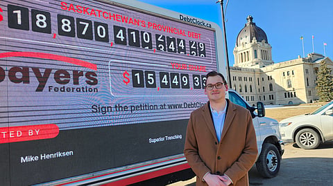 Canadian Taxpayers Federation Prairie Director Gage Haubrich, in front of the Saskatchewan Legislature and the federation's provincial debt clock