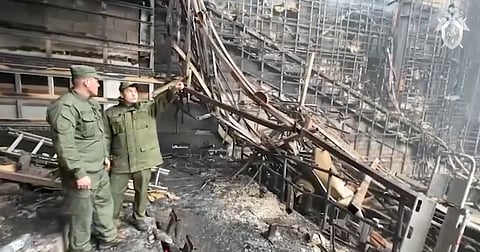Russian officials look over the remains of the concert hall attacked by terrorists