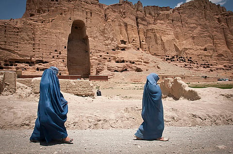 Two women walk past the huge cavity where one of the ancient Buddhas of Bamiyan, known to locals as the "Father Buddha," used to stand, June 17, 2012. The monumental statues were built in AD 507 and 554 and were the largest statues of standing Buddha on Earth until the Taliban dynamited them in 2001. Regina lawyer Gerald Heinrichs compares western outrage over their destruction to the comparitive silence over ongoing attacks on churches in Canada 
