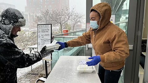 A Fred Victor volunteer hands out food to one of its clients.