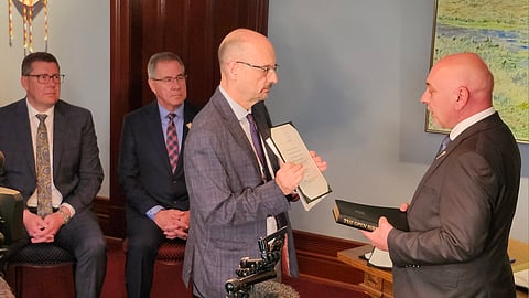 Premier Scott Moe and Lt Governor Russ Merasty watch as Terry Jenson is sworn into cabinet