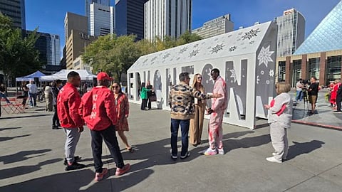 A group of people speaking to one another in Sir Winston Churchill Square in front of the Edmonton Sign. 