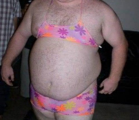 A man wears a child's bikini - place unknown.