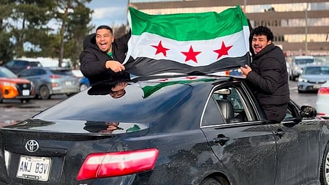 Syrians in Canada raise their rebel flag at a rally at Ottawa's Billings Bridge Shopping Centre, Sunday. Columnist Linda Slobodian argues that as so many Syrians are still receiving public assistance in Canada, it would be a good idea for them to start going home