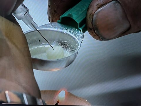An addict  prepares a drug injection at the Sheldon Chumir Safe Consumption Site in Calgary