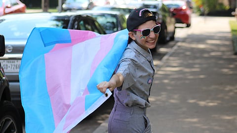 A transgender boy holding the transgender flag 