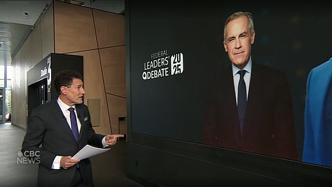 2025 federal English debate moderator Steve Paikin points to an image of Liberal Leader Mark Carney as he walks towards the studio at CBC Radio-Canada in Montreal