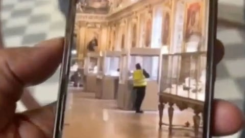 Thieves in high vis vests smash the glass display case at the Louvre