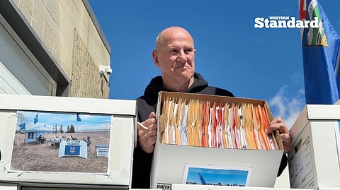 Mitch Sylvestre showcasing a box of signed petition sheets. 