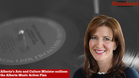 Minister Tanya Fir in front of a backdrop picture of a music record. 