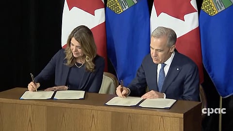 Premier Danielle Smith and Prime Minister Mark Carney signing the agreement in Calgary on May 15, 2026. 
