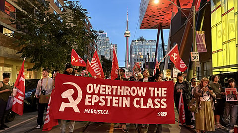 Communist banners and an “Overthrow the Epstein class” sign on the “Many vs. The Money” march toward the AGO, Monday night in downtown Toronto.