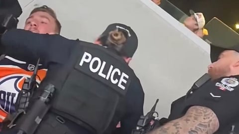 Edmonton police officers removing a fan from Rogers Place after the individual allegedly waved an Alberta flag during an Oilers game. 